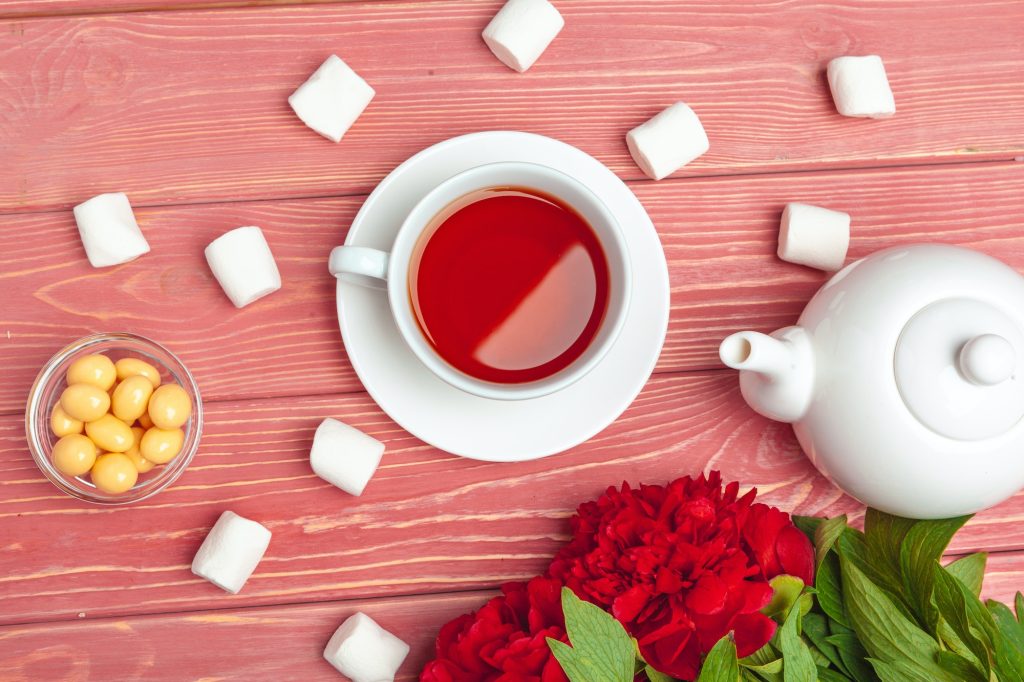 Home 3 Cup of tea with sweets and flowers on wooden table